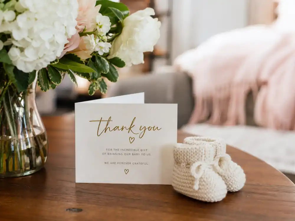 Newborn booties and thank-you card for celebrities who used surrogates list gratitude-to-carrier editorial without identifiable faces