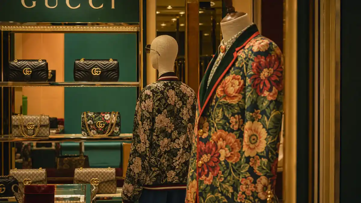 Luxury Gucci boutique interior with bold floral print jackets on mannequins and GG logo handbags illustrating celebrities who wear Gucci red carpet and street style culture