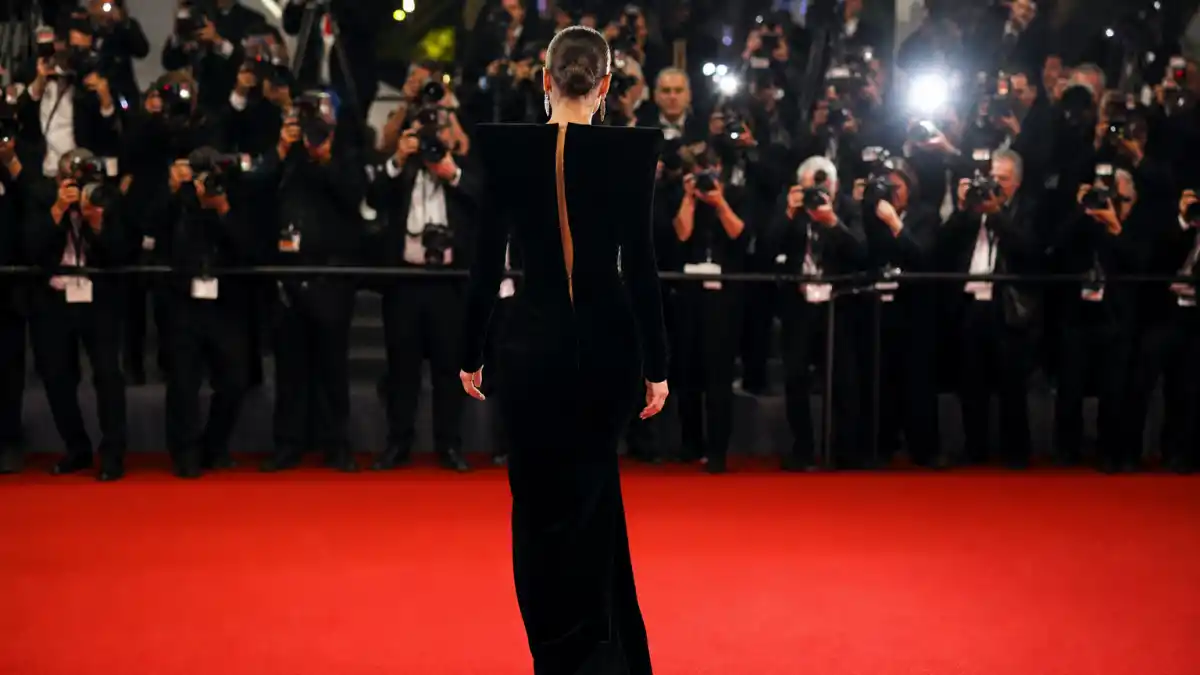 Celebrities who wear Tom Ford — anonymous woman from behind in sharp black velvet column gown walking red carpet at luxury premiere