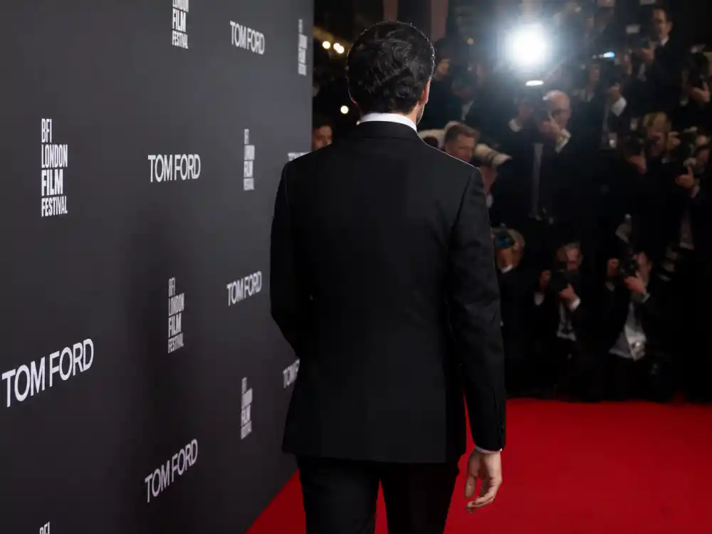 Anonymous man from behind in peak-lapel black tuxedo on red carpet step-and-repeat for celebrities who wear Tom Ford menswear