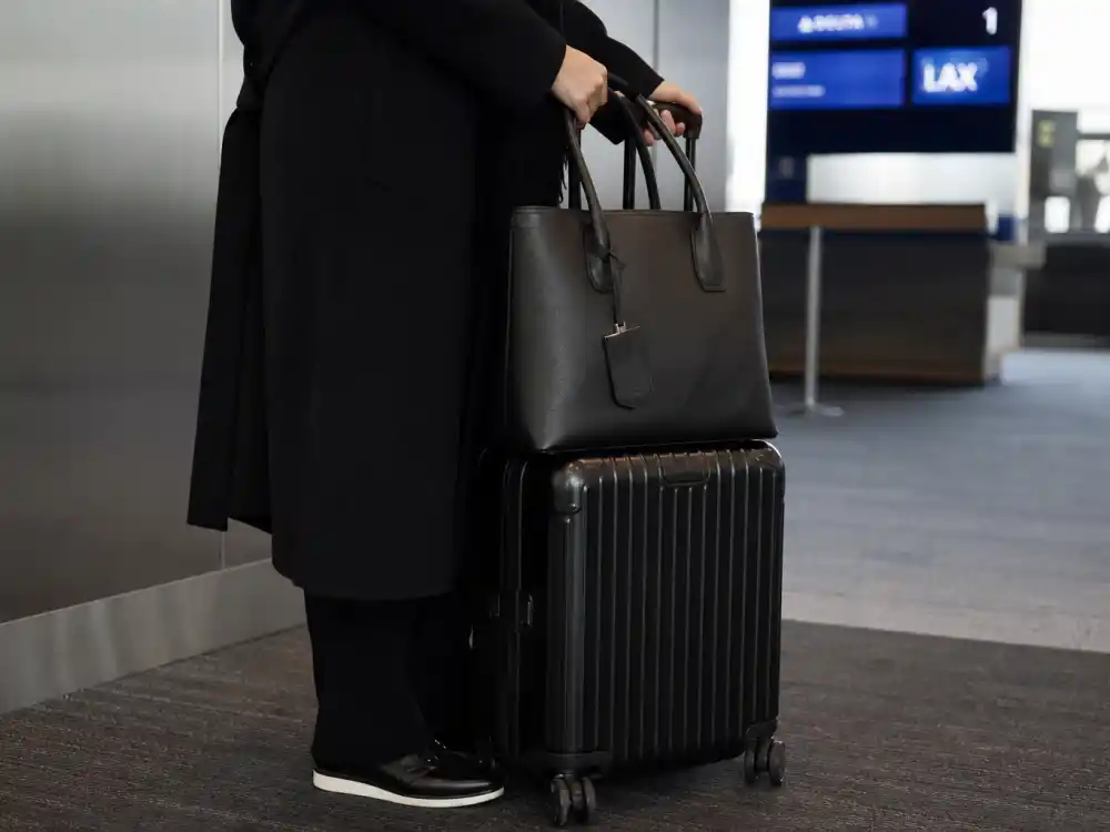 Sleek black rolling carry-on and structured leather tote elevating celebrity airport fashion street style luggage styling