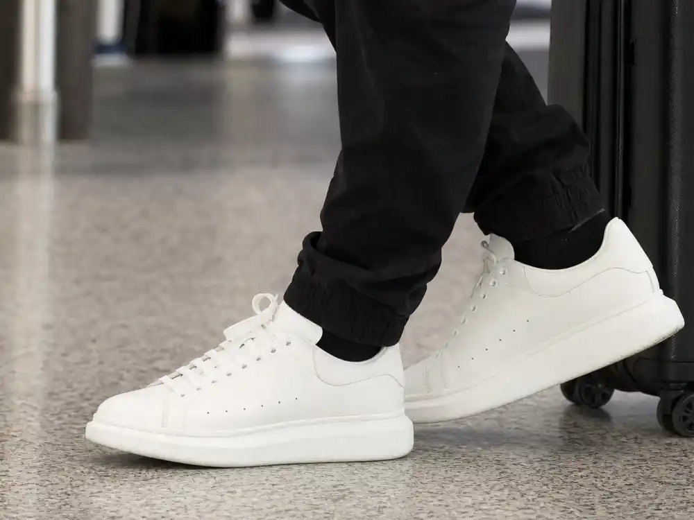 Pristine white leather sneakers with black joggers defining celebrity airport fashion street style elevated casual footwear
