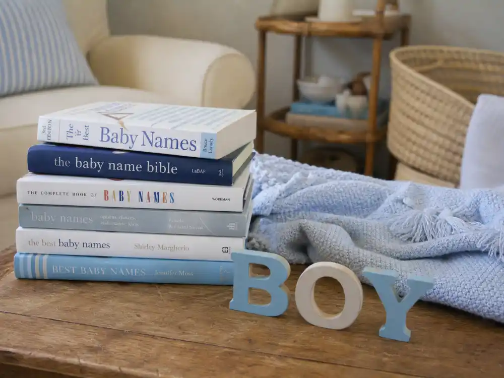 Trending baby boy name books stacked on coffee table with blue nursery blanket — celebrity baby boy names inspired by stars drive search spikes hours after every verified star birth reveal