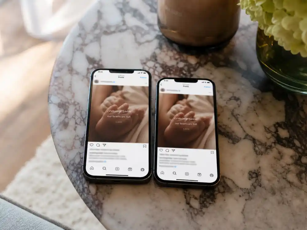 Two smartphones with matching posts for celebrity birth announcements Instagram 2026 synchronized couple reveal trend on a marble coffee table