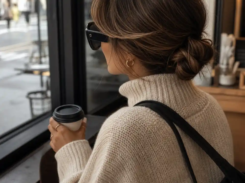 Oversized black sunglasses on cream knit finishing celebrity casual errands style 2026 face-framing accessory layer at coffee shop