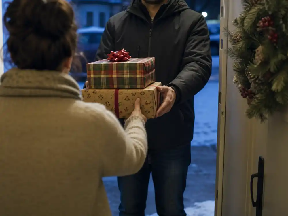 Holiday gift handoff from behind for celebrity co-parenting holiday traditions doorway exchange editorial without identifiable faces