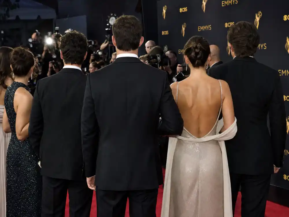Awards premiere red carpet with anonymous figures in designer gowns and tuxedos showing red carpet visibility celebrity designer brand ambassadors 2026 leverage every season