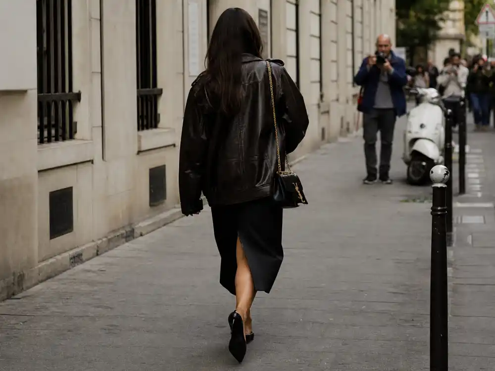 Street style celebrity get the look stylist tips with leather jacket midi skirt and designer bag on anonymous sidewalk frame from behind