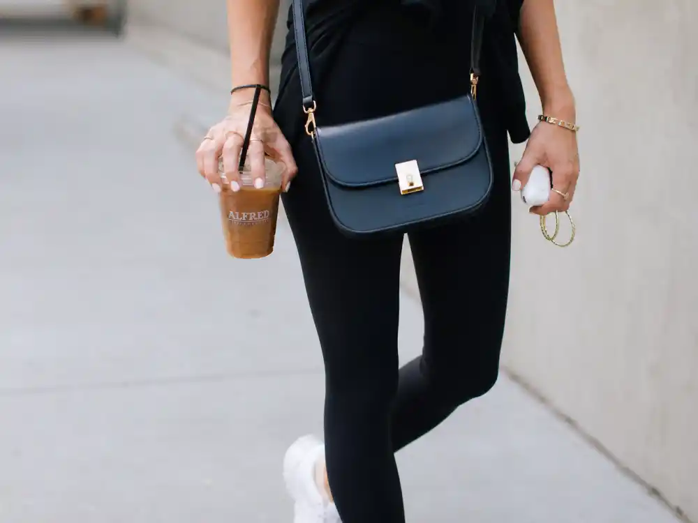 Gold hoops crossbody bag and iced coffee finishing celebrity gym to street style outfits accessory layer on sidewalk