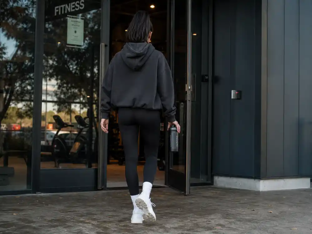 Black leggings and oversized charcoal hoodie forming the athleisure base of celebrity gym to street style outfits at gym exit