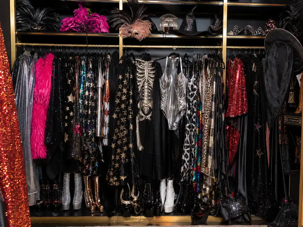 Open closet with celebrity Halloween costumes 2026 wardrobe essentials sequined capes feathered masks metallic bodysuits and witch hats on velvet hangers