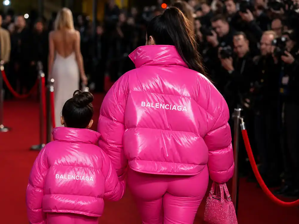 Matching hot pink puffer jackets on parent and child from behind at red carpet rope for celebrity kids twinning outfits with parents Stormi Kylie coordinated looks