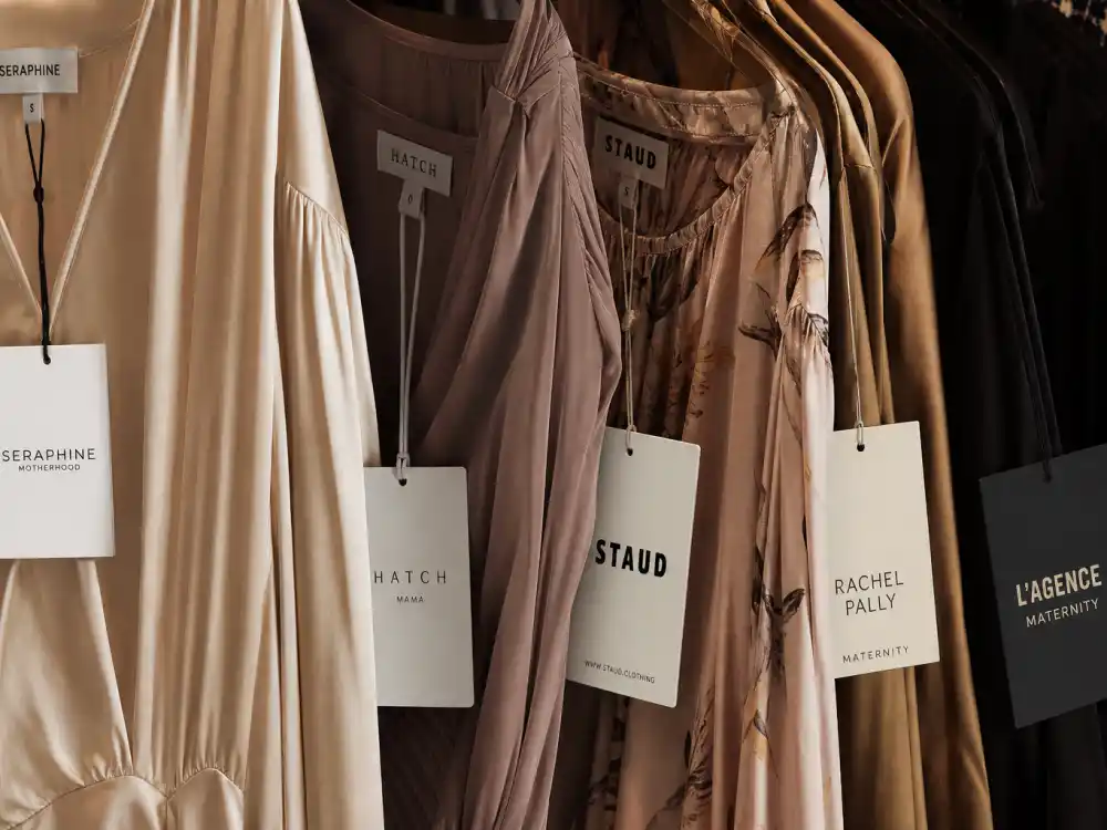 Designer hang tags on silk maternity gowns illustrating celebrity maternity dress brands label and sourcing detail in luxury boutique