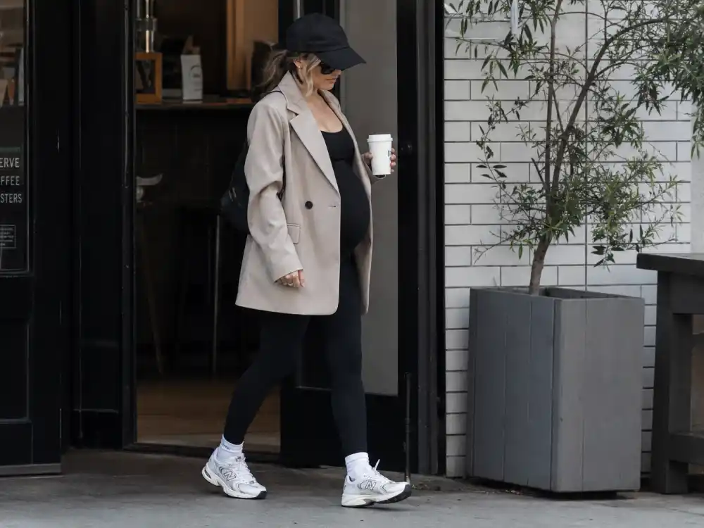 Off-duty celebrity maternity fashion street style with oversized blazer leggings and sneakers outside coffee shop
