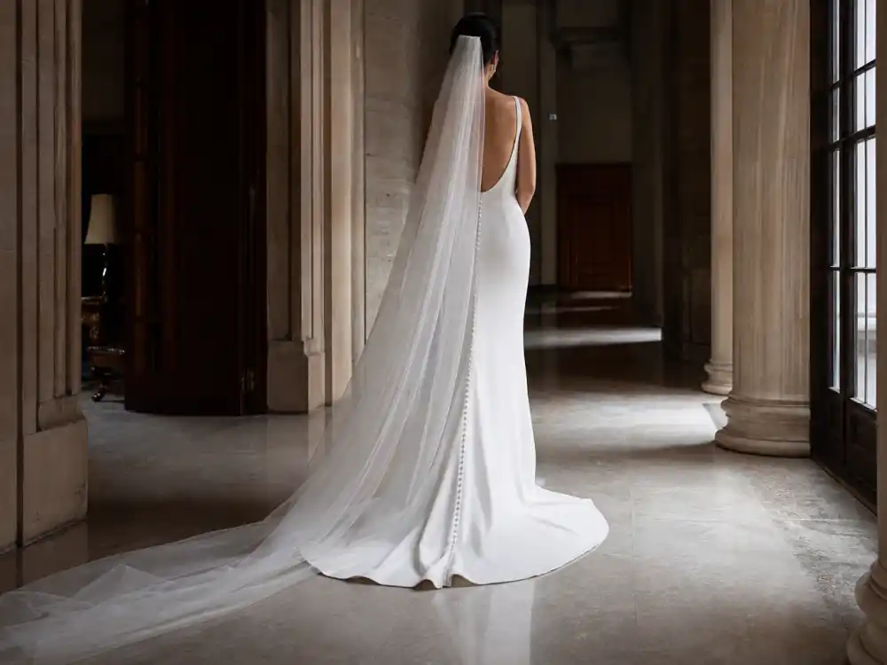 Minimal train sweeping stone hallway completing the proportion discipline behind iconic celebrity minimalist wedding dress trends