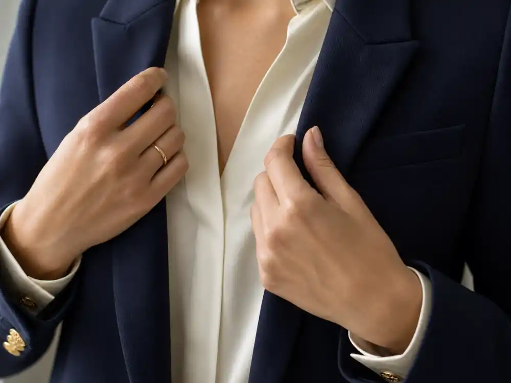 Hands adjusting structured navy blazer lapels over silk blouse defining celebrity office chic outfit inspiration tailoring codes stylists repeat on press tours