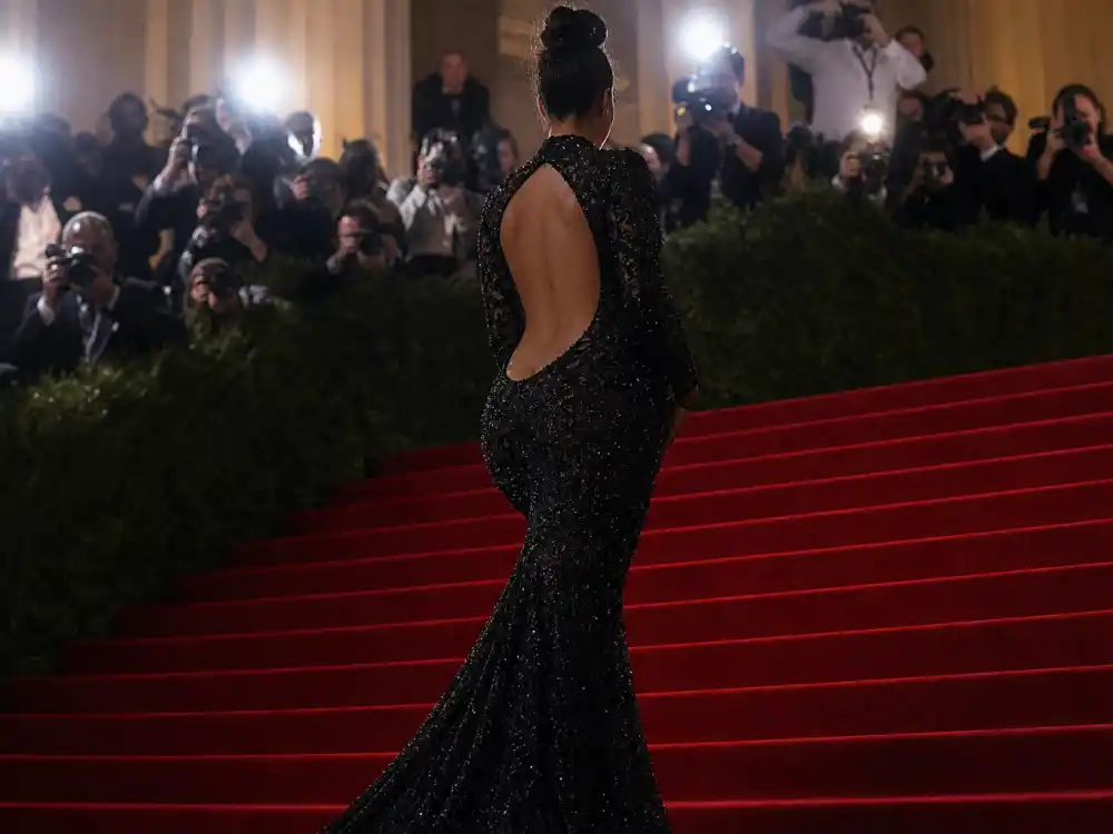Met Museum grand staircase red carpet for celebrity pregnancy reveal ideas red carpet — anonymous guest ascending gala steps in formal gown from behind