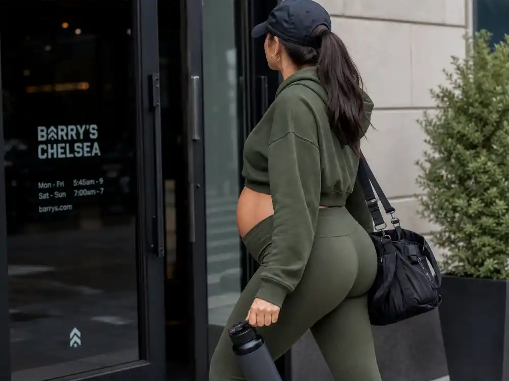 Anonymous pregnant woman in olive athleisure set leaving gym exit for celebrity pregnancy street style 2026 post-workout off-duty maternity looks