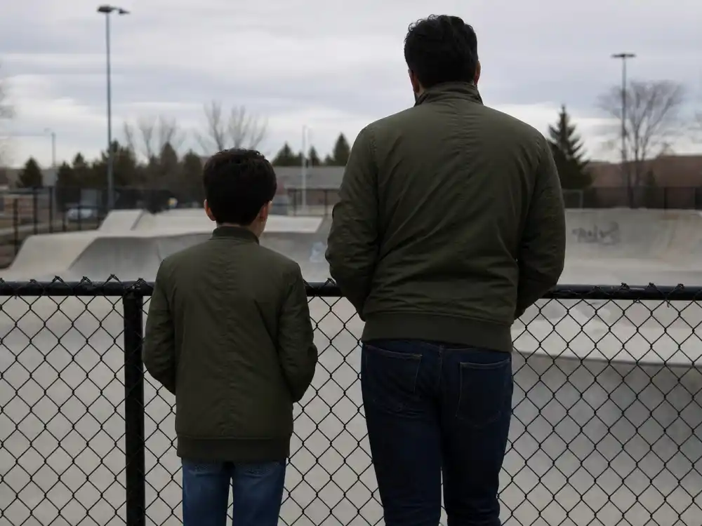 Matching olive bomber jackets on father and teen son silhouettes from behind for celebrity sons who look like their dads Mason Scott Disick co-parenting lane