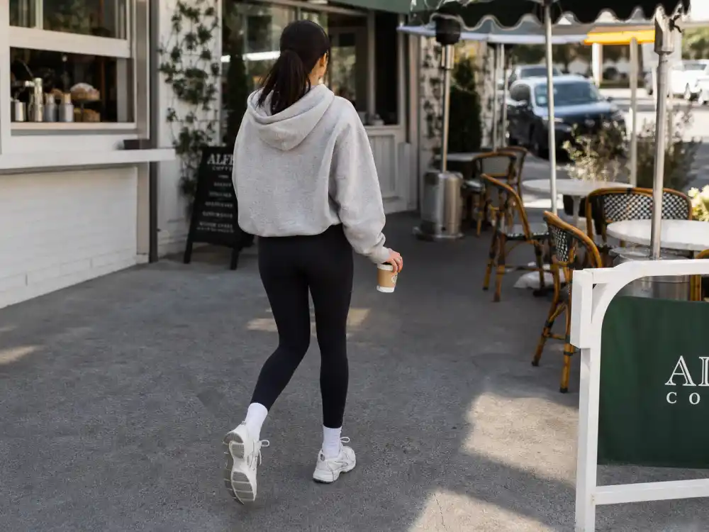 Grey hoodie black leggings and white sneakers on coffee run showing celebrity street style athleisure morning formula at outdoor cafe