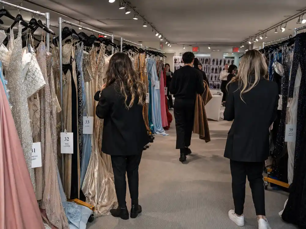 Haute couture evening gowns on rolling racks in designer showroom where celebrity stylists pick red carpet looks from satin sequin and velvet options