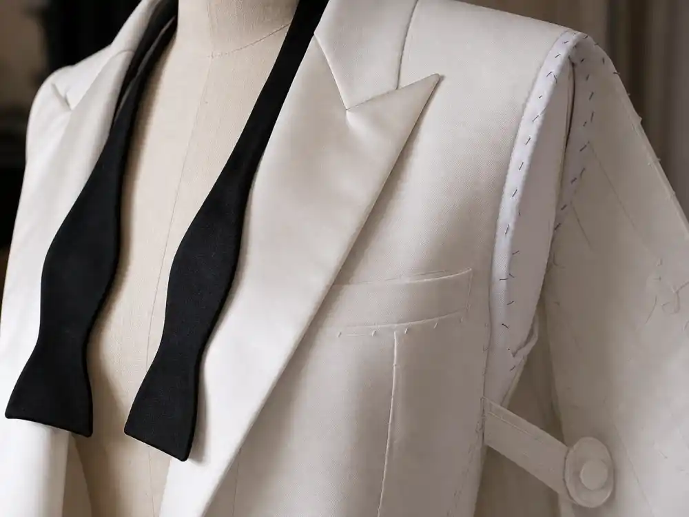 Close-up white satin lapels and reversed tailcoat seam detail defining Celine Dion reverse tuxedo Grammys textile craftsmanship and formalwear subversion