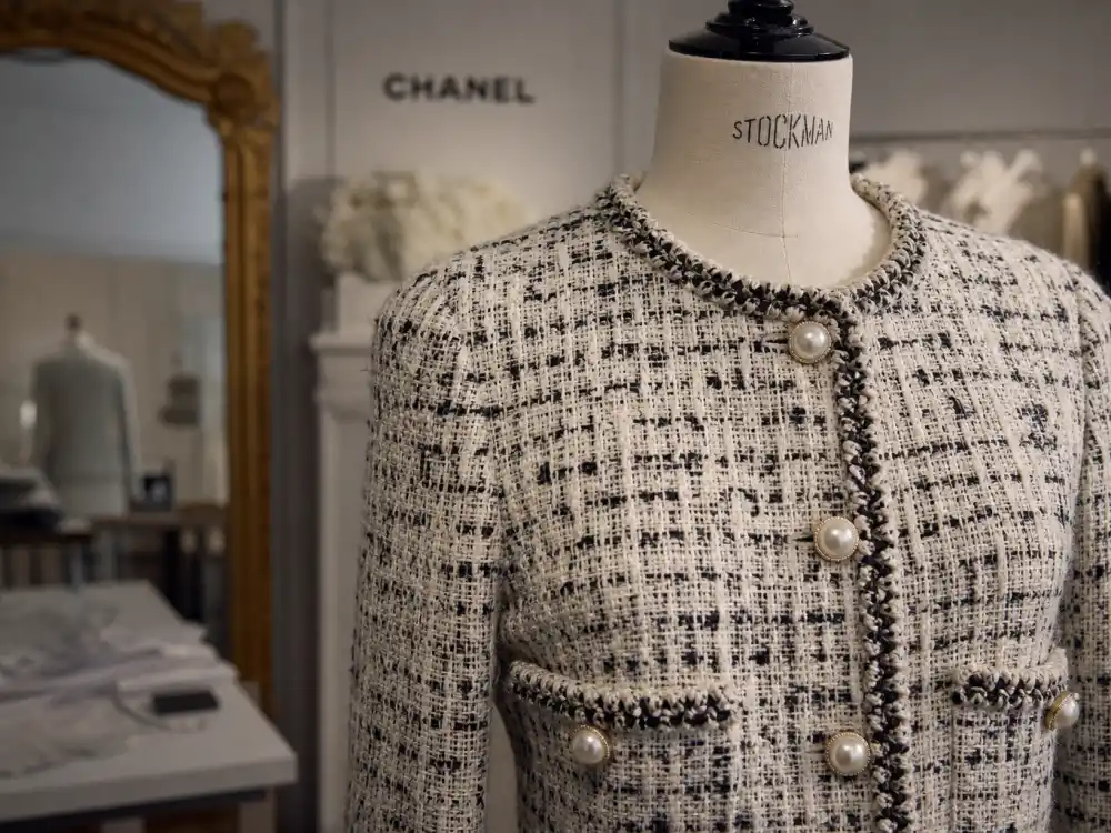 Classic Chanel tweed boucle jacket on dress form showing pearl buttons and texture codes behind iconic Chanel celebrity red carpet looks on and off the carpet