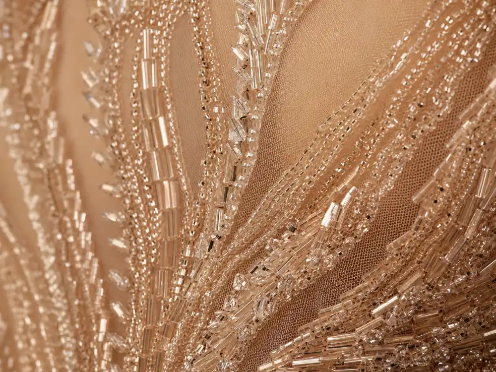 Hand-sewn crystal beadwork technique defining Cher naked dress Bob Mackie history — macro detail of nude illusion gown construction