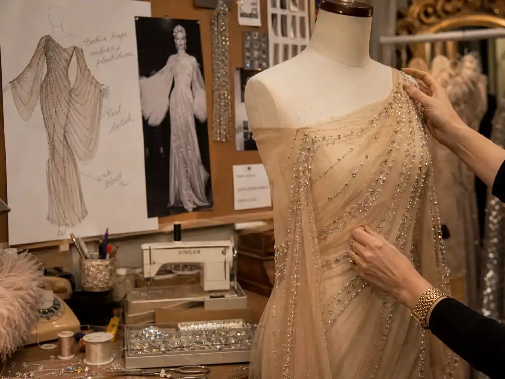 Bob Mackie atelier costume design workspace behind Cher naked dress Bob Mackie history — sheer gown draped on couture dress form with bead sketches