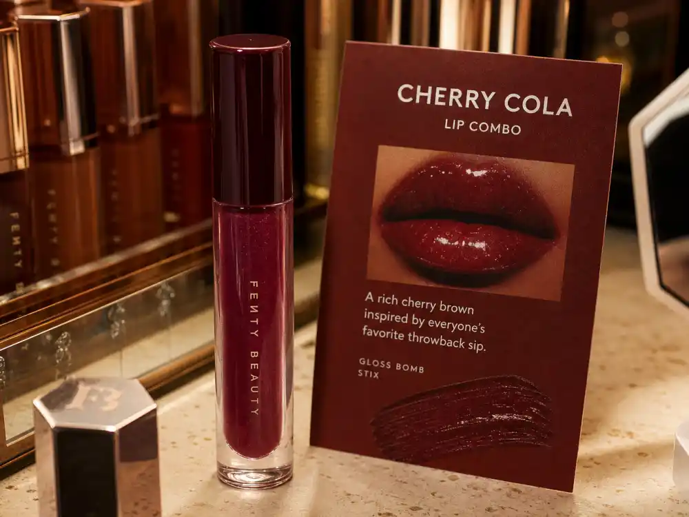 Glossy cherry cola lip gloss tubes and warm red-brown swatch card defining cherry cola beauty celebrity trend lip color codes