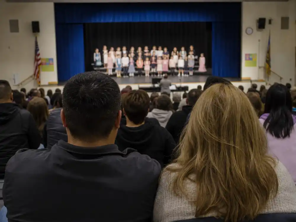 School auditorium from behind for Chris Martin Gwyneth Paltrow co-parenting Apple Moses joint attendance privacy editorial without identifiable faces