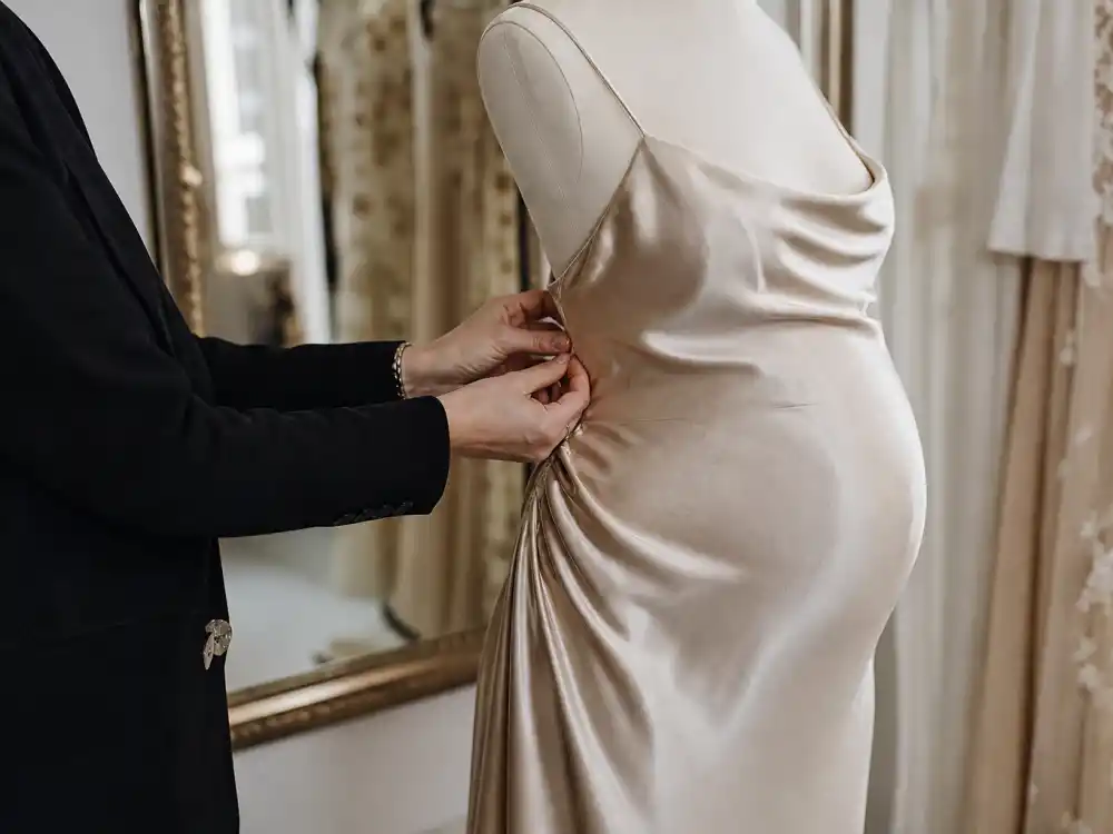 Couture fitting room adjusting champagne silk slip on pregnant dress form for Chrissy Teigen maternity style outfits designer bump engineering moment