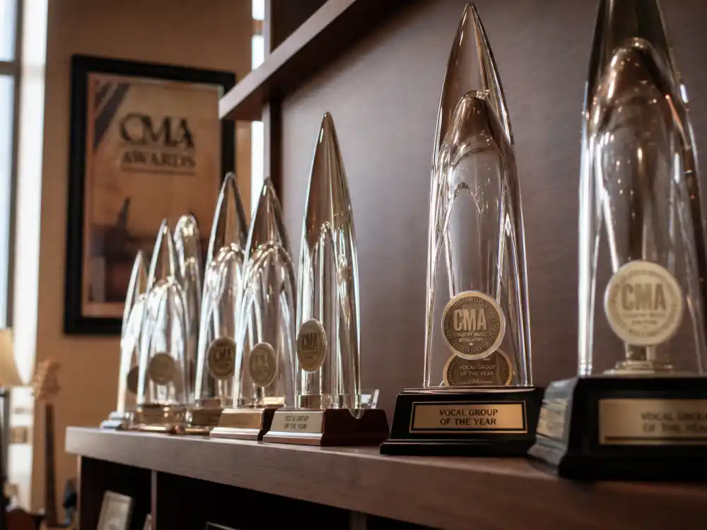 Shelf lined with CMA Awards glass trophies illustrating all-time totals for the most CMA awards won by an artist