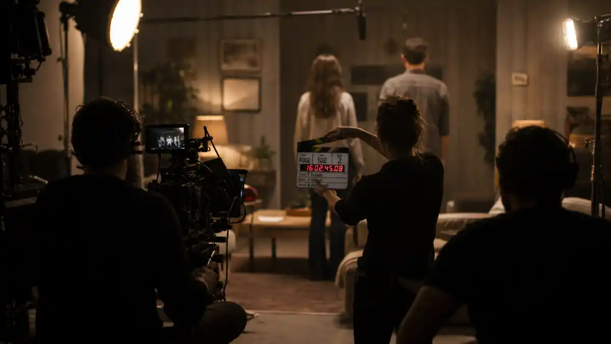 Dakota Johnson celebrity kid acting career — indie film set from behind with anonymous crew silhouettes and clapperboard editorial milestone without identifiable faces