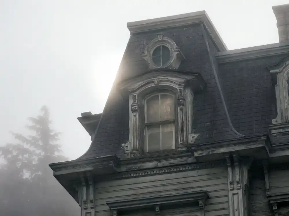 A foggy Victorian mansion attic window evoking Devon Sawa as Casper McFadden in the 1995 Casper film