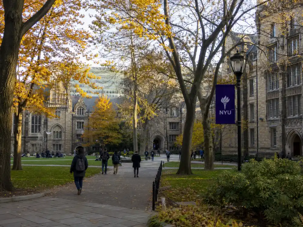 A prestigious university campus quad in autumn where Dylan Sprouse studied at NYU after leaving Disney