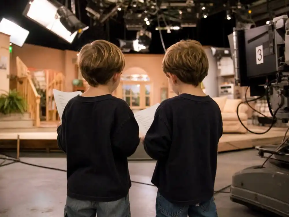 Anonymous twin child actors on a 1990s sitcom soundstage evoking the early Dylan Sprouse and Cole Sprouse careers