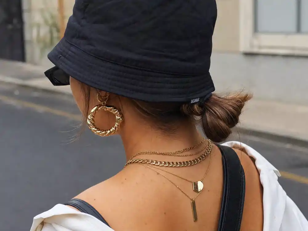 Layered gold chains narrow 90s sunglasses and bucket hat finishing Emily Ratajkowski street style outfits accessory layer