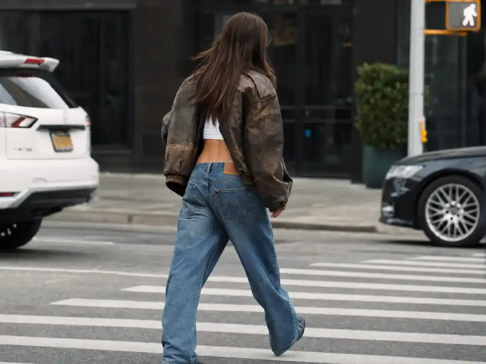 Oversized vintage leather jacket over crop top and wide leg jeans defining Emily Ratajkowski street style outfits layering