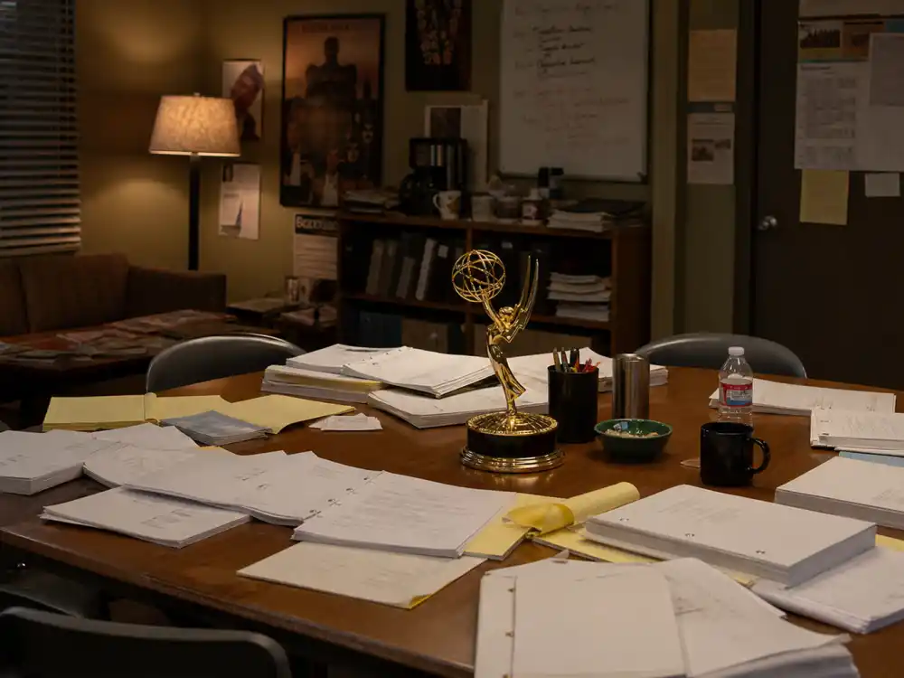 Television writers room with scripts scattered on table reflects prestige-era Emmy best drama winners by year from The West Wing through Succession