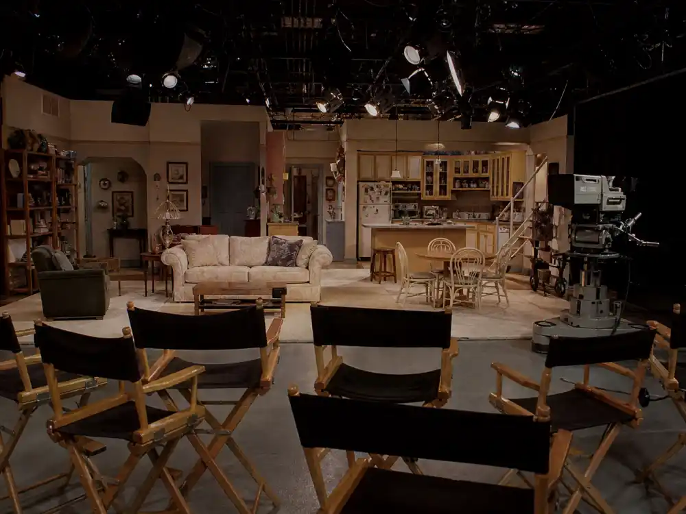 Empty 1990s sitcom soundstage with couch and studio lights for Family Matters cast where are they now behind-the-scenes context