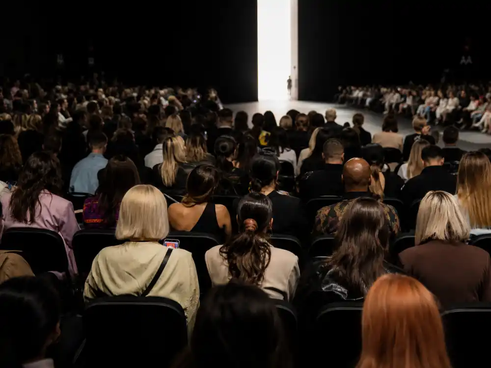 Fashion week celebrity sightings 2026 front row seating with anonymous well-dressed guests seen from behind before runway show begins