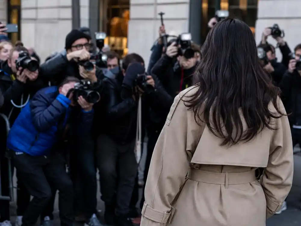 Paparazzi photographers capturing anonymous celebrity from behind in designer coat during fashion week celebrity sightings 2026 sidewalk moment