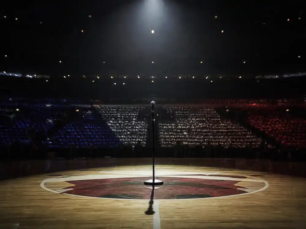 Empty arena spotlight on center court microphone evoking what happened to Fergie after the 2018 NBA All-Star national anthem performance