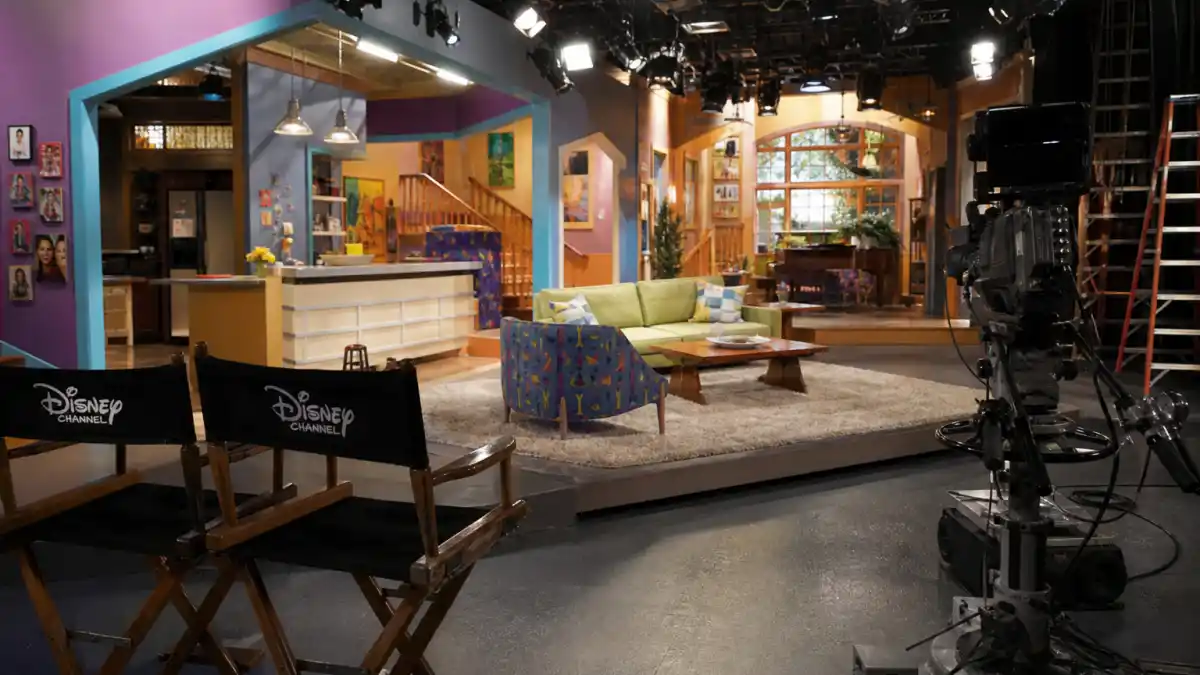 Former Disney Channel stars where are they now — colorful 2000s kids network soundstage evoking the golden era of Disney teen sitcoms
