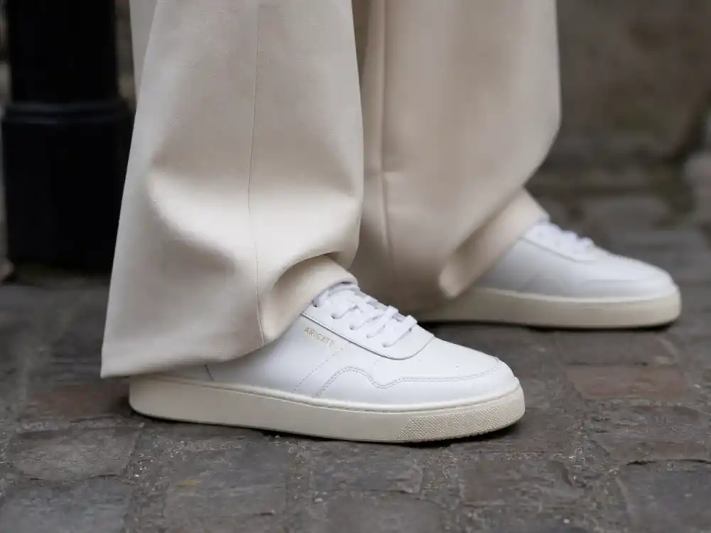 Pristine white leather sneakers with cream trousers showing Gigi Hadid street style 2026 elevated footwear codes