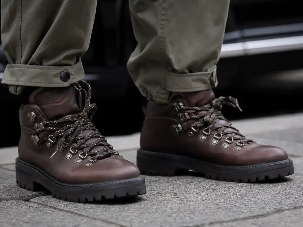 Close-up of brown hiking boots with lug soles and olive technical pants for gorpcore celebrity street style footwear detail