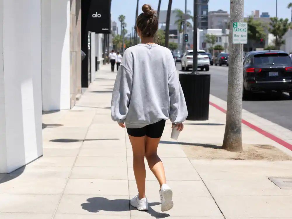 Oversized grey sweatshirt and black biker shorts illustrating Hailey Bieber street style looks sports-luxe formula
