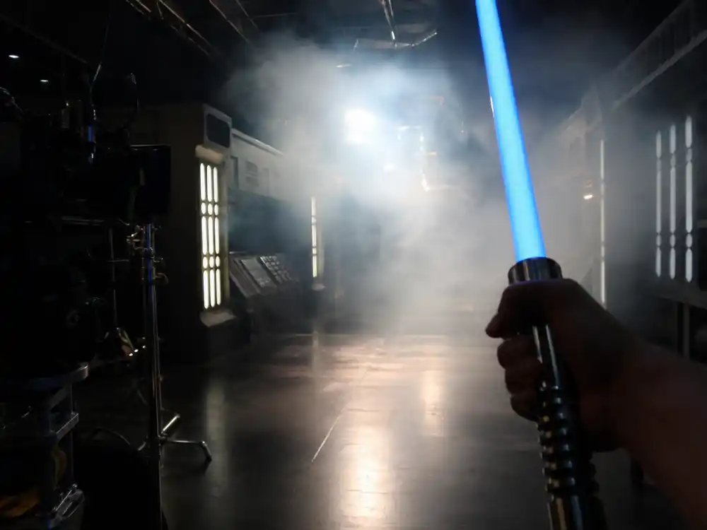A sci-fi soundstage with a glowing blue blade prop, evoking the Hayden Christensen Anakin Skywalker prequel years