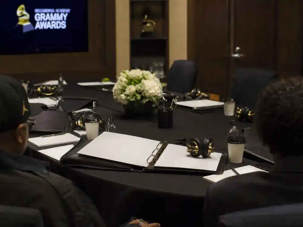 Review committee screening binders on a conference table explain the gatekeeping layer before members vote on how are Grammy winners chosen